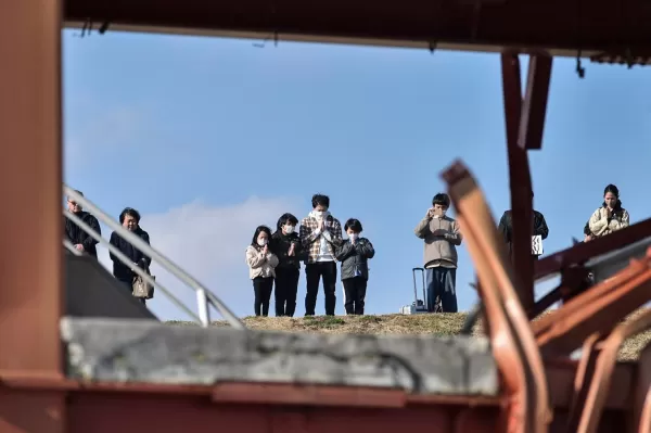 People pray as they take part in a minute's silence to remember the victims on the 14th anniversary of the 2011 earthquake, tsunami and nuclear disaster. Photo by STR/JIJI PRESS/AFP via Getty Images.